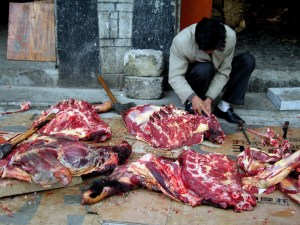 A butcher prepares yak meat outside the Potala Palace